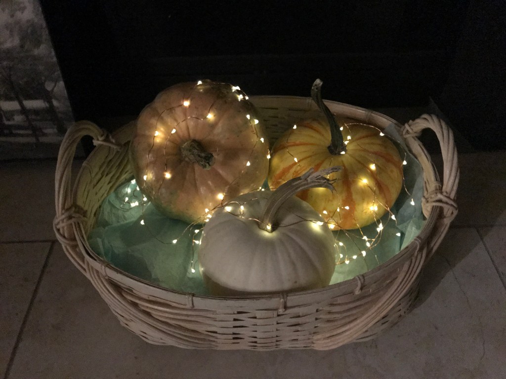 Decorating a fireplace with pumpkins, lighting, and a basket.